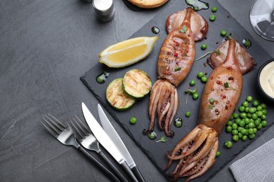 Tasty grilled squids served on black table, flat lay. Space for text