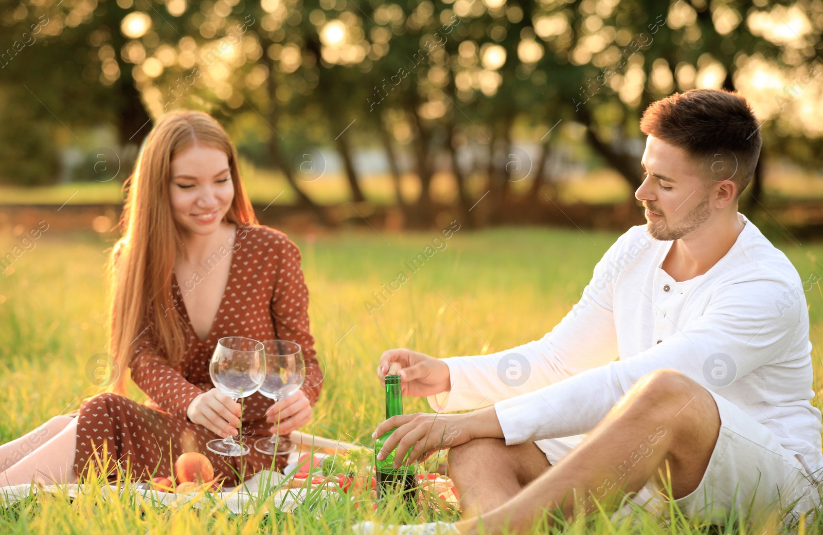 Photo of Young man and his girlfriend having picnic in green park