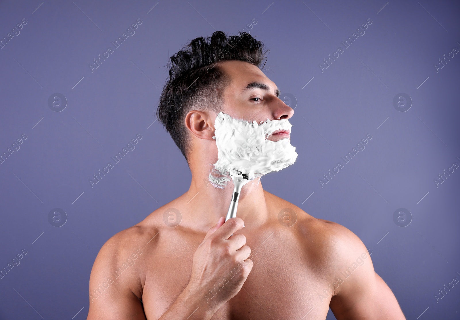 Photo of Handsome young man shaving on color background