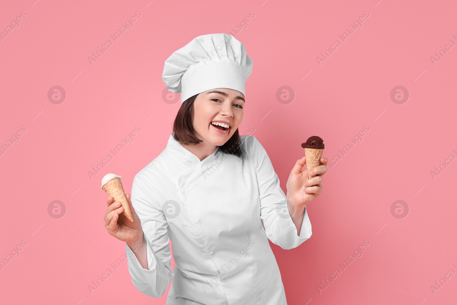 Photo of Happy confectioner with delicious ice cream cones on pink background