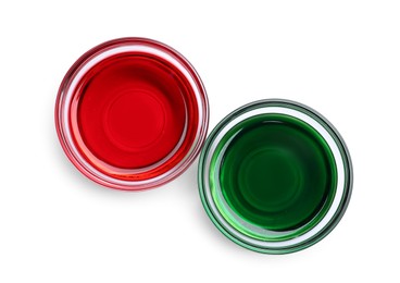 Glass bowls with red and green food coloring on white background, top view