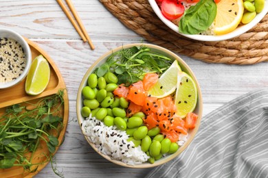 Photo of Delicious poke bowls with fish and edamame beans on white wooden table, flat lay
