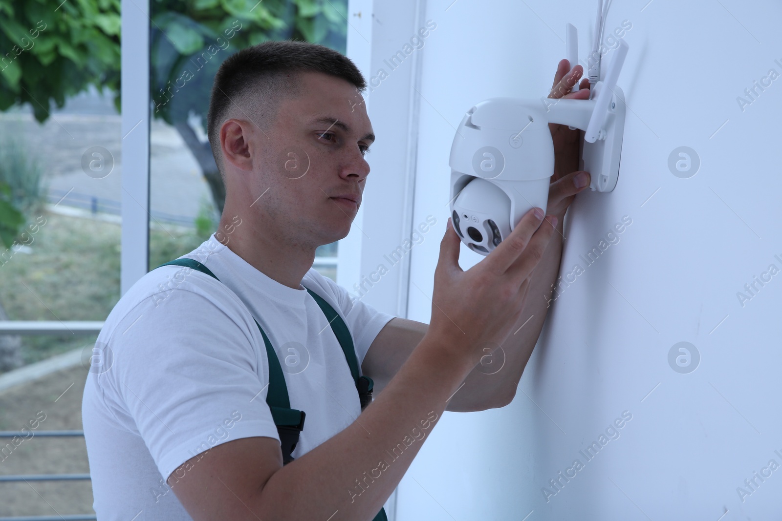 Photo of Technician installing CCTV camera on wall indoors