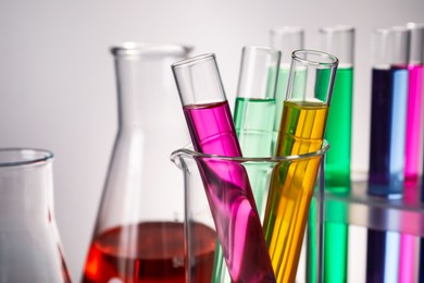 Photo of Different laboratory glassware with colorful liquids on grey background, closeup