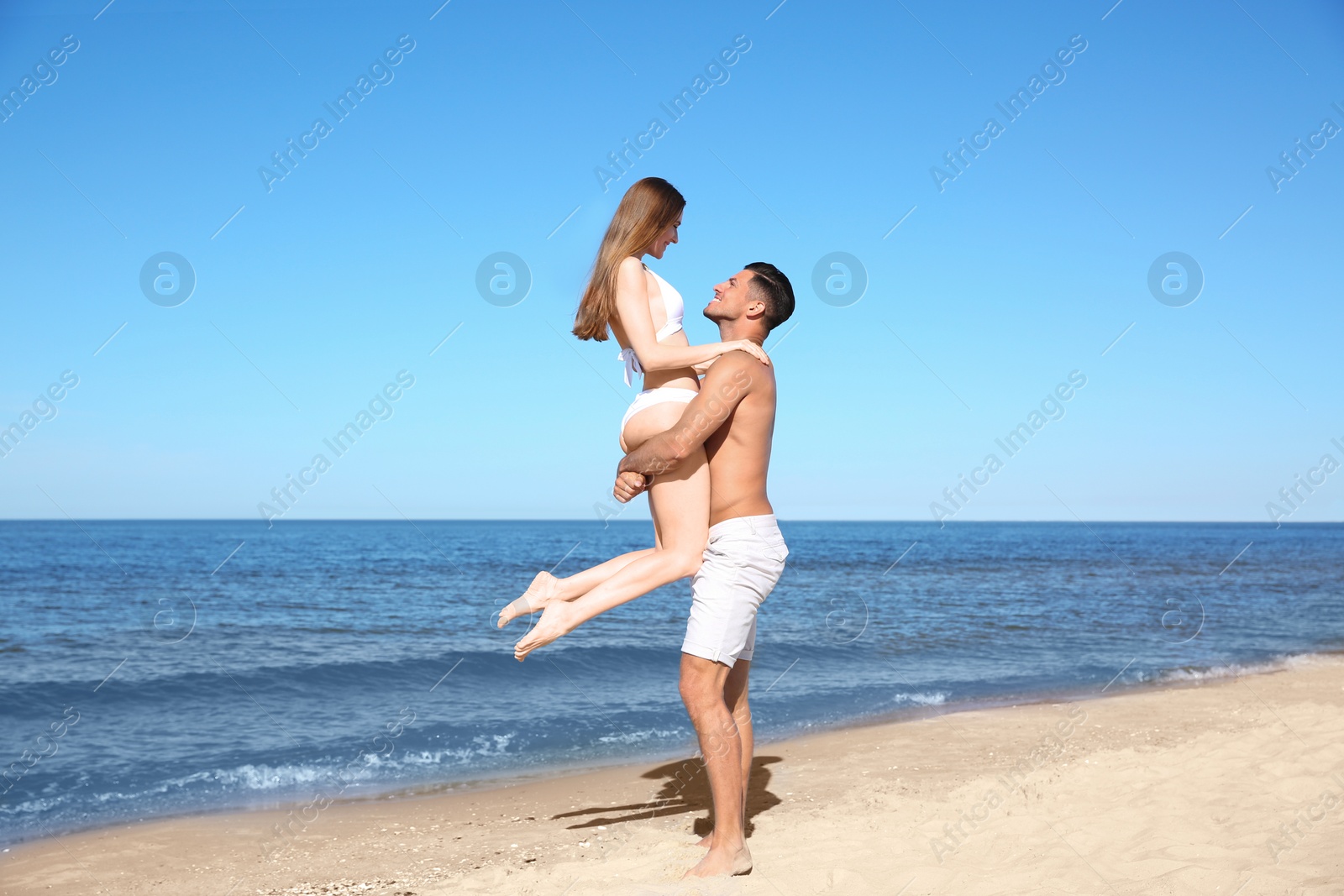 Photo of Woman in bikini and her boyfriend on beach. Happy couple