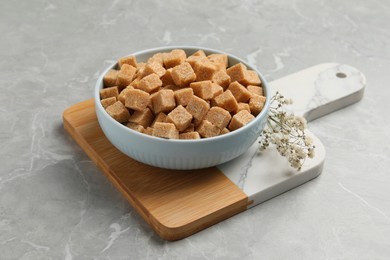 Bowl of brown sugar cubes on light grey marble table