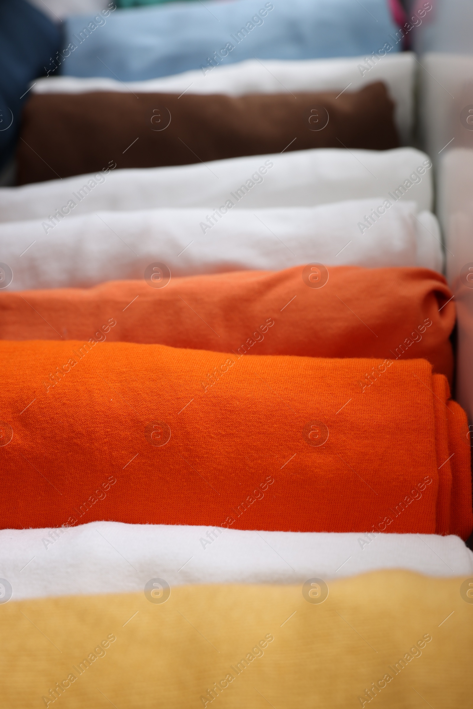 Photo of Different rolled shirts in drawer, closeup. Organizing clothes