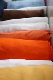 Photo of Different rolled shirts in drawer, closeup. Organizing clothes