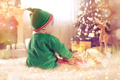 Image of Baby in cute elf costume near Christmas gift on floor at home, back view. Magical festive atmosphere