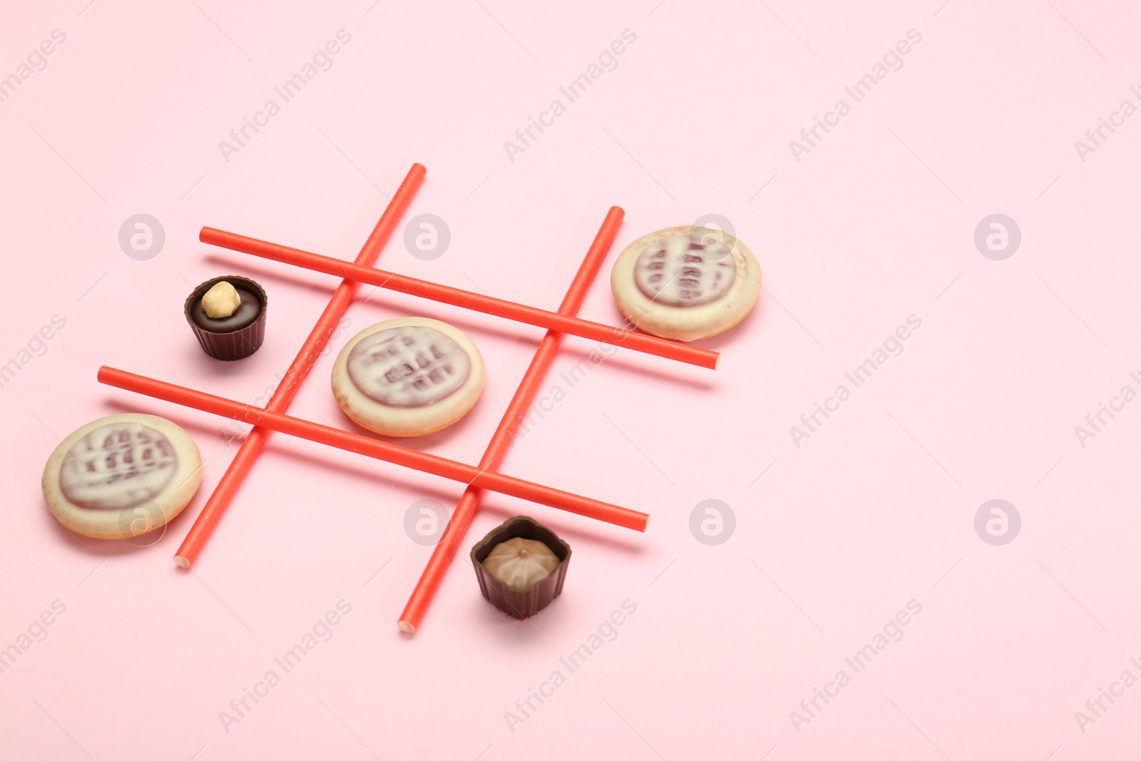 Photo of Tic tac toe game made with cookies and sweets on pink background