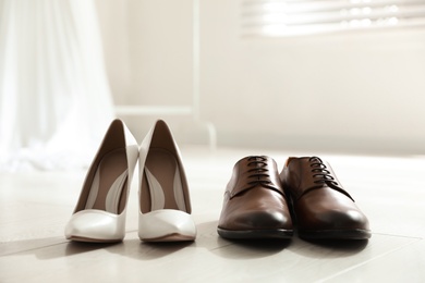 Photo of Wedding shoes for bride and groom on white wooden floor indoors