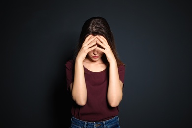 Photo of Young woman covering face against dark background
