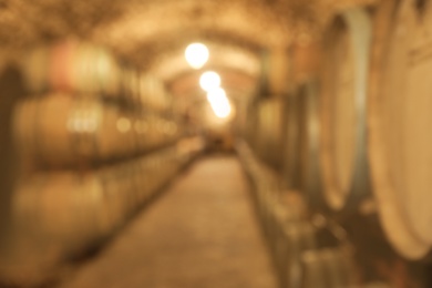 Photo of Blurred view of wine cellar with large wooden barrels