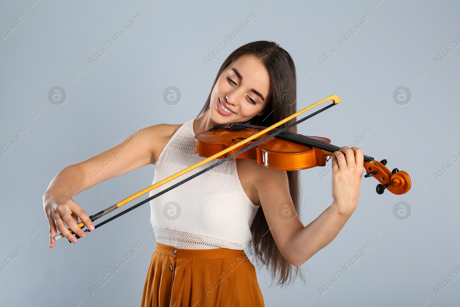 Photo of Beautiful woman playing violin on grey background