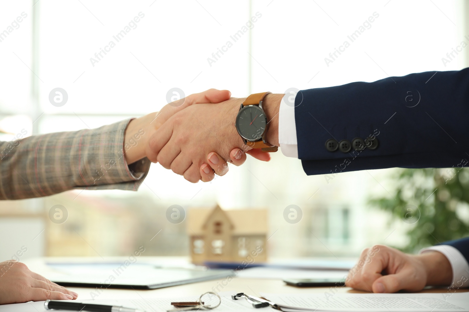 Photo of Real estate agent shaking hands with client in office, closeup