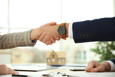 Photo of Real estate agent shaking hands with client in office, closeup