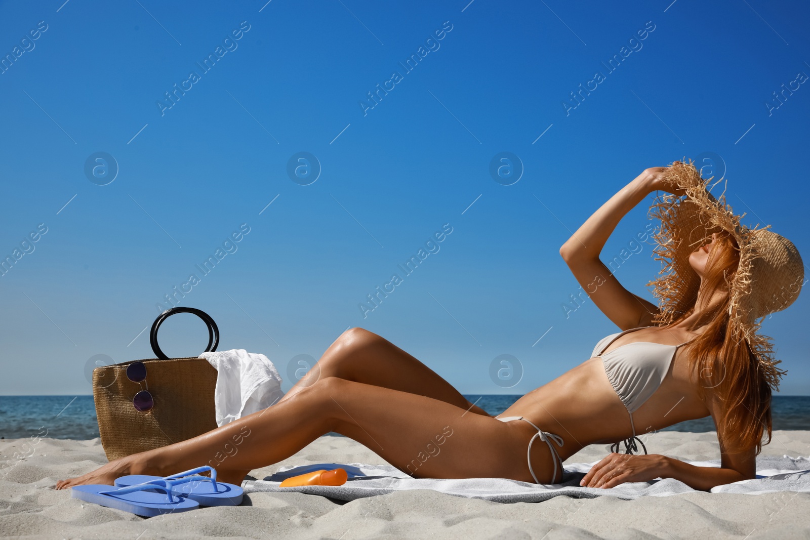 Photo of Woman with beach bag and straw hat on sand near sea