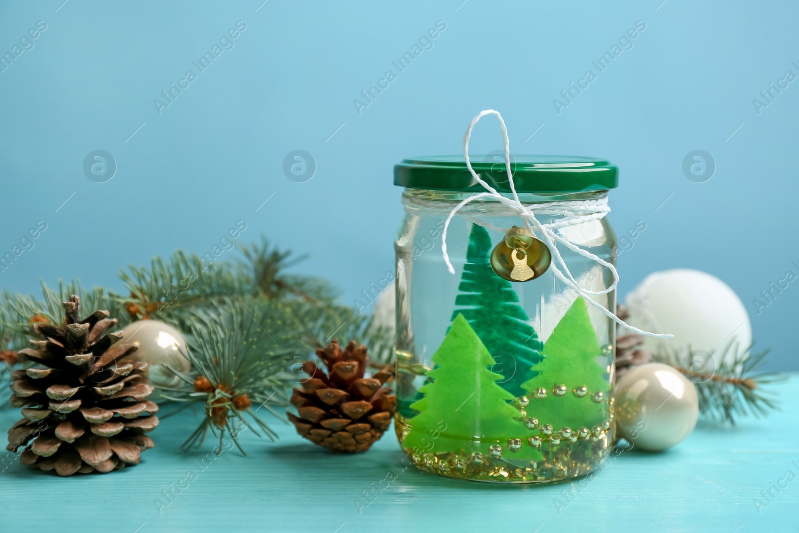 Photo of Handmade snow globe and Christmas decorations on light blue background