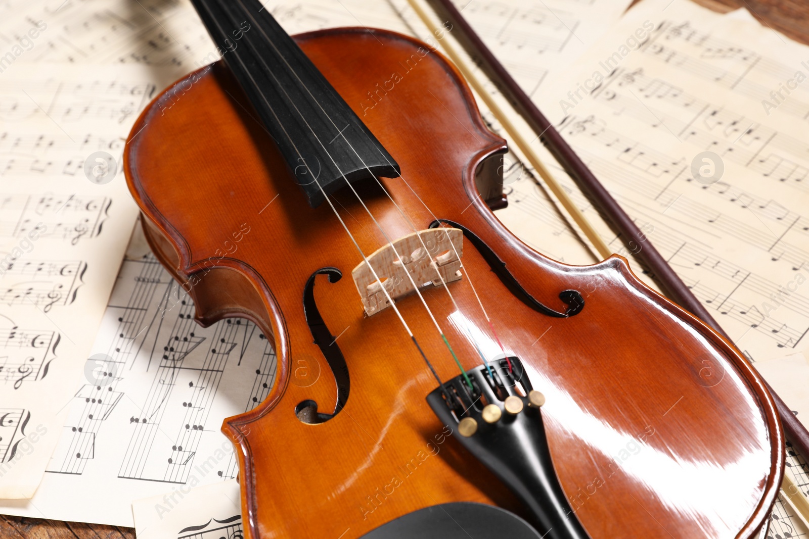 Photo of Violin, bow and music sheets on table, closeup