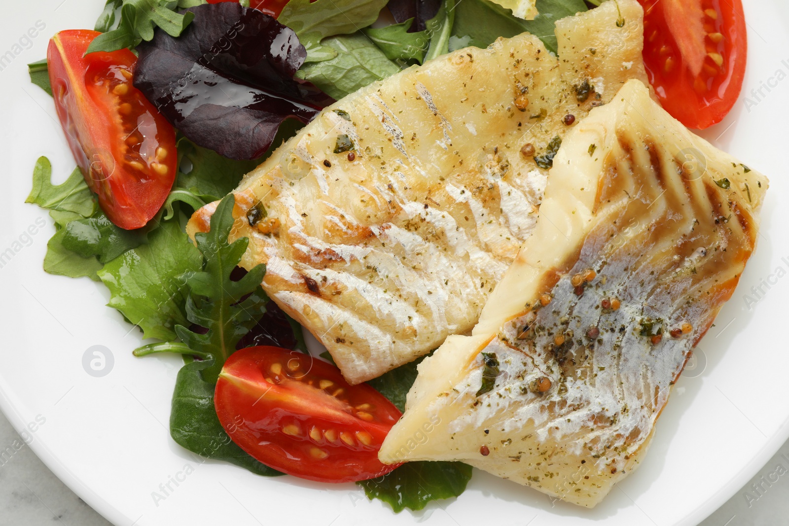 Photo of Tasty cod cooked served with salad on white table, top view