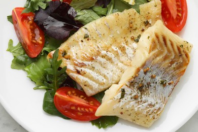 Tasty cod cooked served with salad on white table, top view