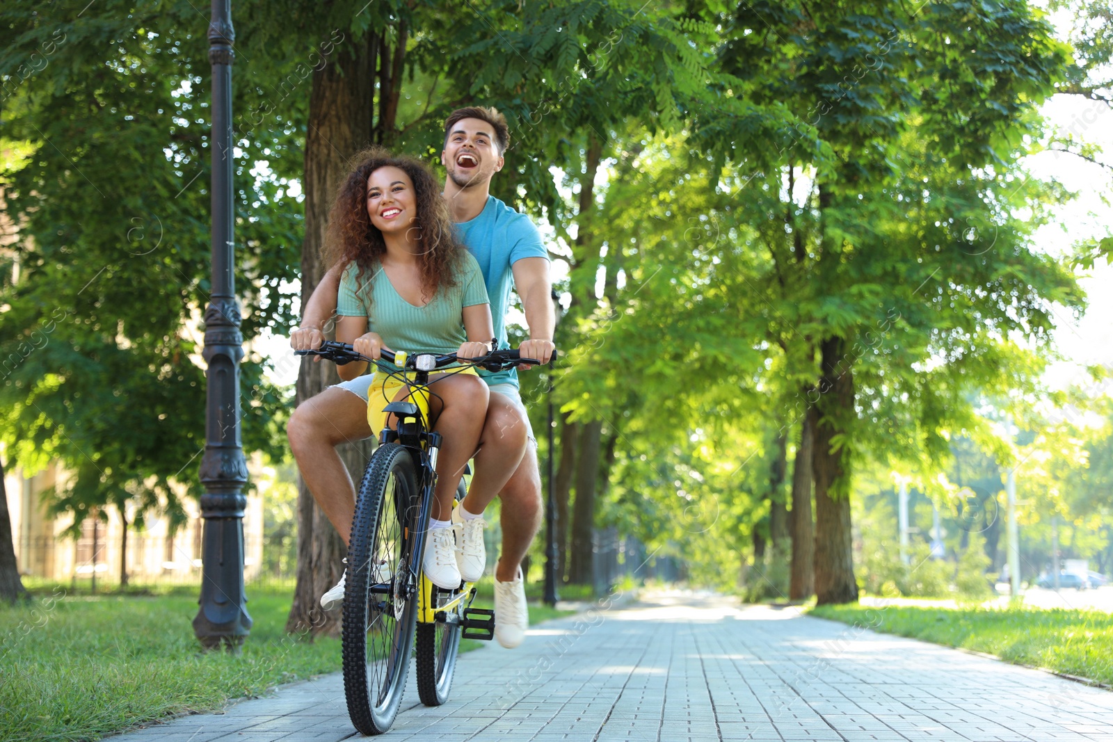 Photo of Happy young couple riding bicycle on city street