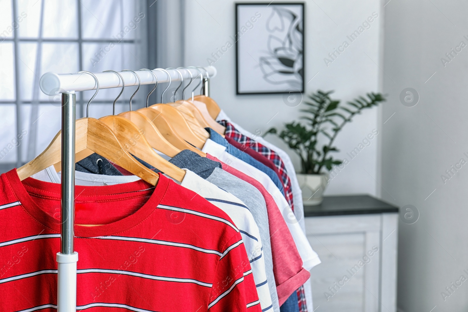 Photo of Stylish clothes hanging on wardrobe rack indoors, closeup. Space for text