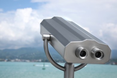 Photo of Metal tower viewer installed near sea. Mounted binoculars