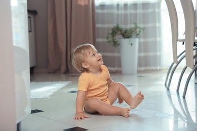 Photo of Cute baby sitting on floor in room. Learning to walk