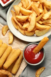 Different snacks and tasty ketchup on table, flat lay