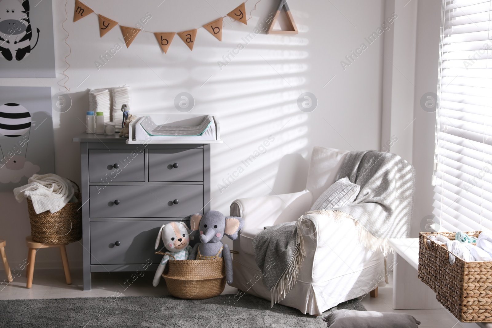 Photo of Chest of drawers with changing tray and pad in baby room. Interior design