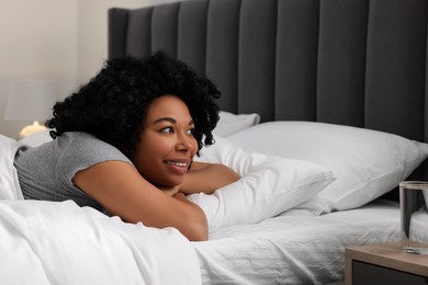 Beautiful young woman lying in soft bed at home