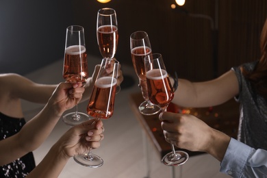 Photo of Friends clinking glasses with champagne on blurred background, closeup