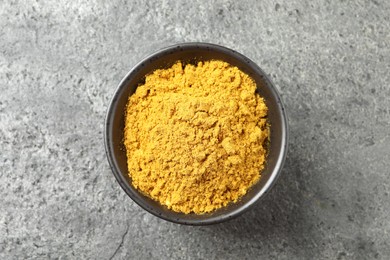 Dry curry powder in bowl on dark textured table, top view