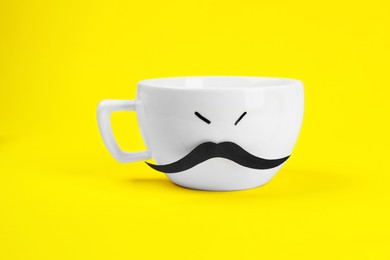 Photo of Man's face made of cup and fake mustache on yellow background