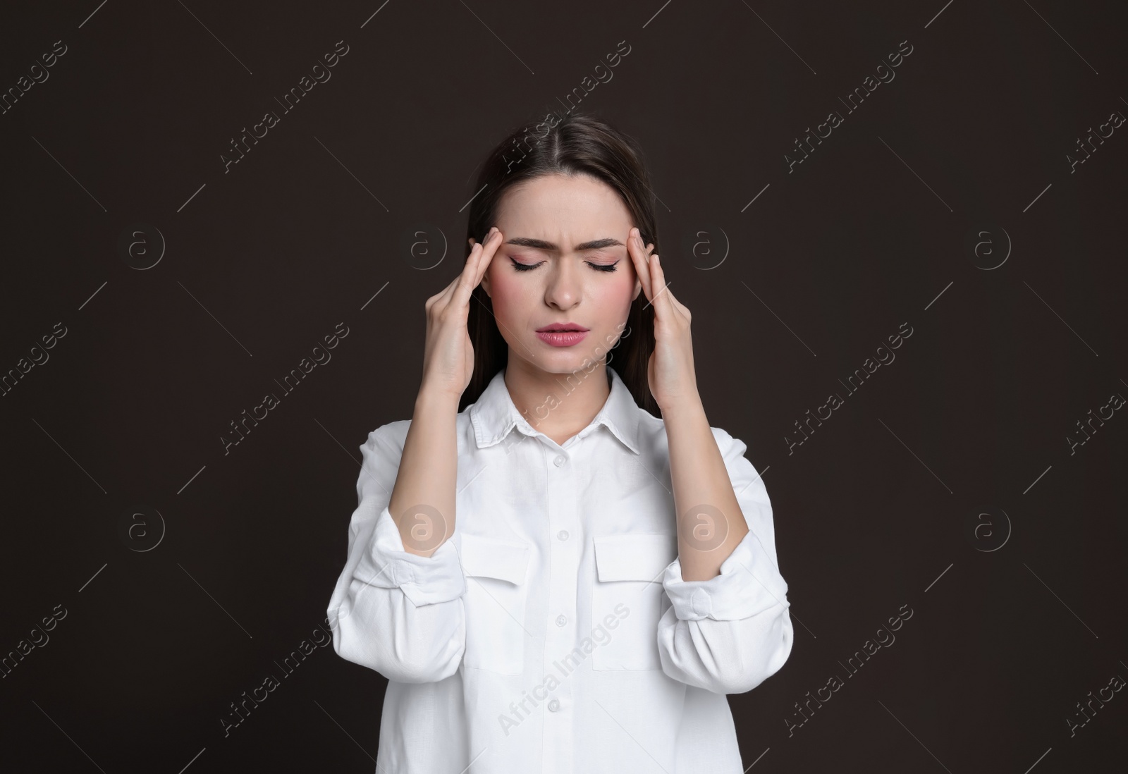 Photo of Young woman suffering from headache on brown background