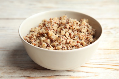 Photo of Cooked delicious quinoa in bowl on  wooden table