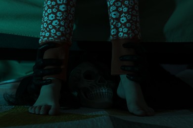 Photo of Scary monster under bed grabbing little girl by legs in darkness, closeup
