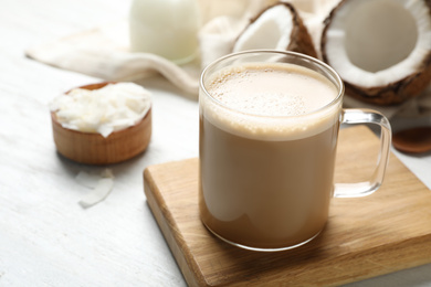 Photo of Delicious coffee with organic coconut oil on white wooden table