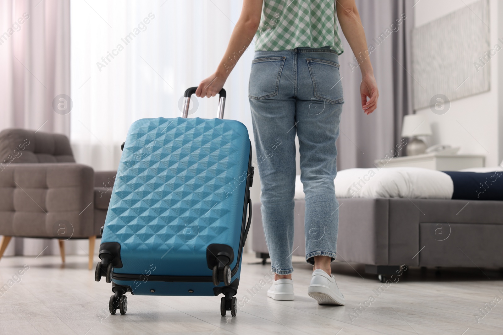 Photo of Guest with suitcase walking in hotel room, closeup