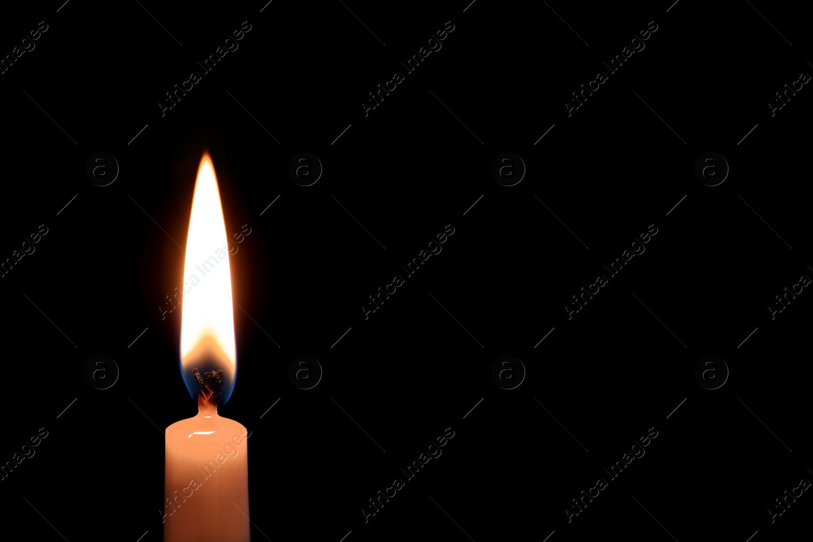 Photo of Wax candle burning on black background