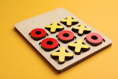 Photo of Tic tac toe set on yellow background, closeup