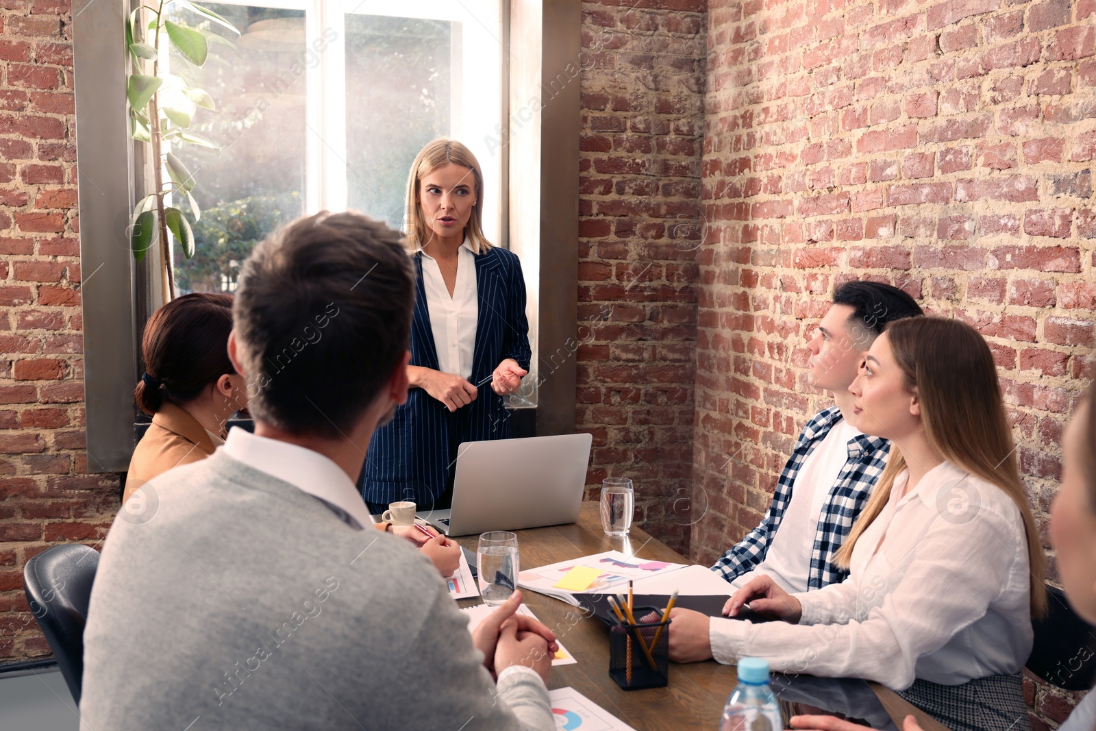 Photo of Businesswoman having meeting with her employees in office. Lady boss