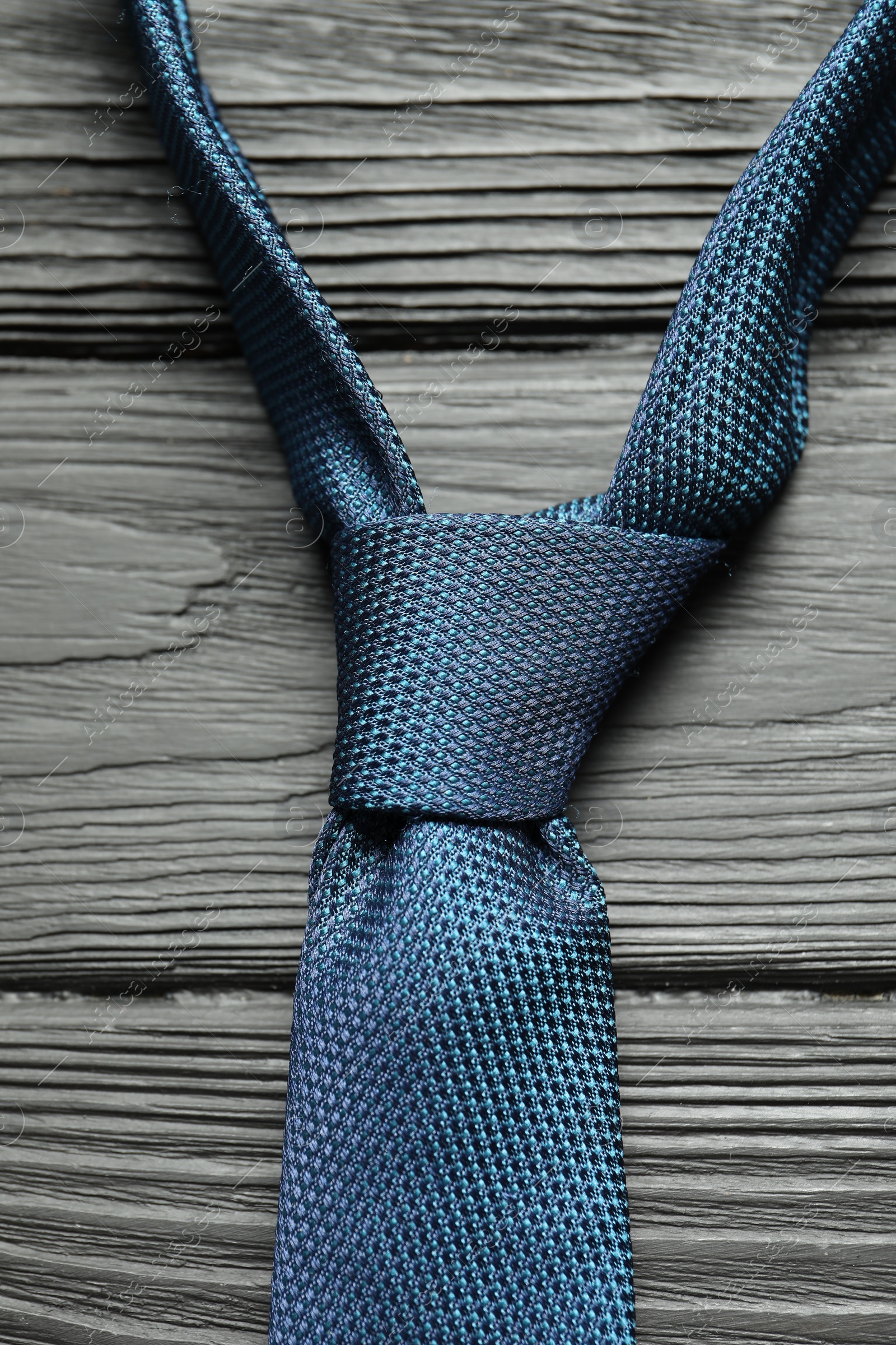 Photo of One blue necktie on black wooden table, top view