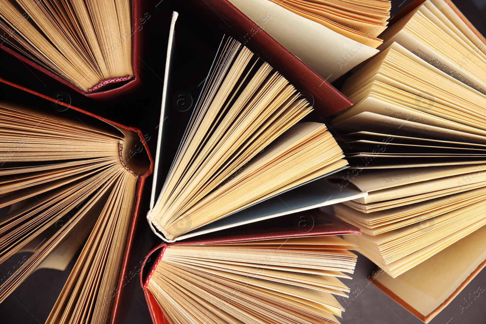 Photo of Many different hardcover books on dark background, top view