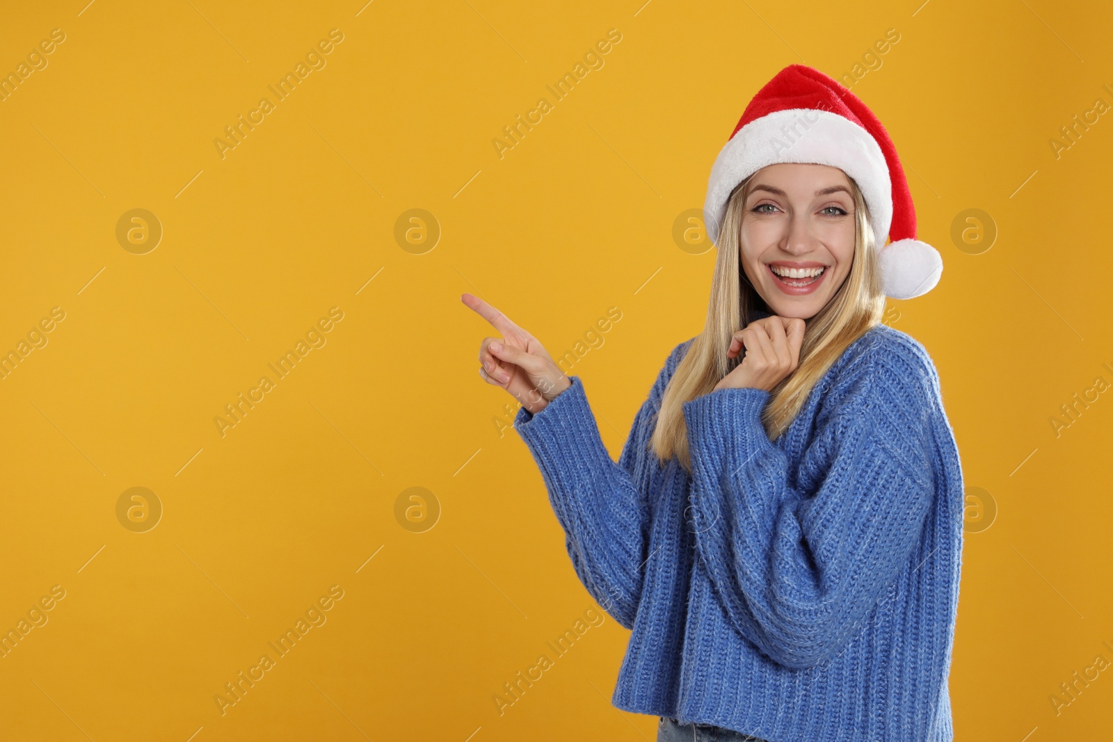 Photo of Happy woman in Santa hat on yellow background, space for text. Christmas countdown