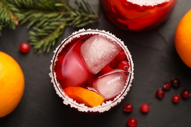 Photo of Tasty cranberry cocktail with ice cubes in glasses on dark gray table, flat lay