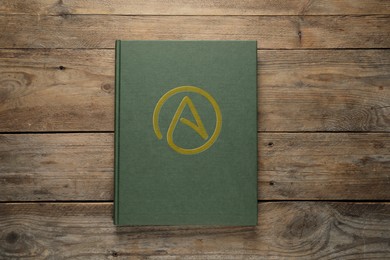 Image of Book with atheism symbol on wooden background, top view
