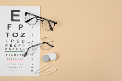 Photo of Vision test chart, glasses, lenses and tweezers on beige background, flat lay. Space for text