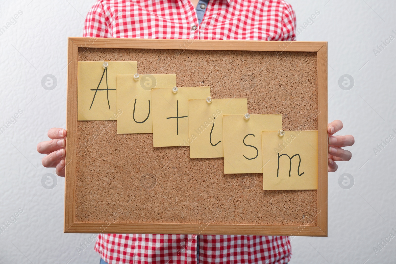 Photo of Woman holding board with word "Autism" on light background